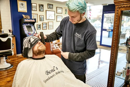 Bond's Barbershop Broadstone - Barber trimming the beard of a customer