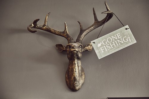 Bond's Barbershop Wareham - Metal stag head mounted on the wall with a gone fishing sign